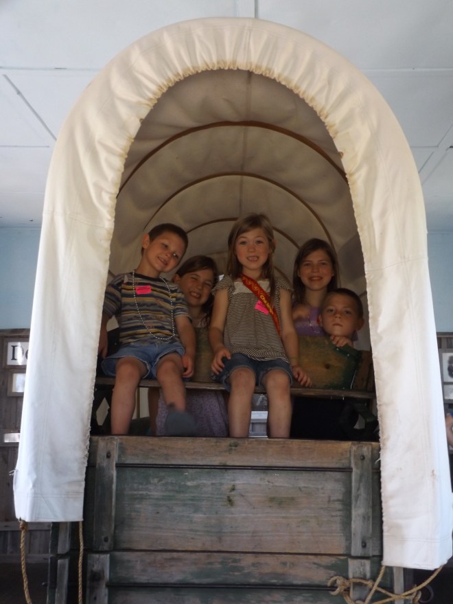 The kids in the back of a covered wagon.